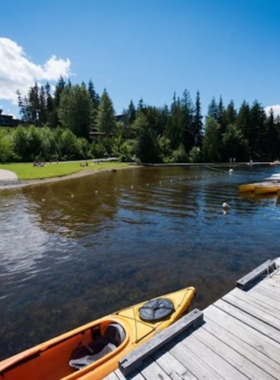 This image shows a peaceful paddleboarding scene on Alta Lake, with a person gliding across the calm waters on a paddleboard. The reflection of the sky and mountains shimmers on the lake’s surface. Tall evergreen trees surround the area, creating a relaxing and picturesque atmosphere. This image captures the perfect summer activity in Whistler, where visitors can enjoy nature and tranquility on the water.