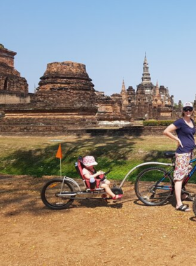 This image shows a group of cyclists enjoying a full-day tour of Sukhothai’s Historical Park, stopping for lunch while learning about the rich history of the temples and ancient ruins along the way.