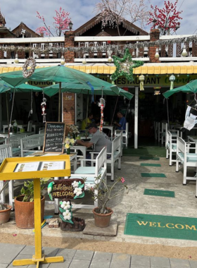 This image shows a picturesque view of Chanda’s Historical Garden Restaurant. The seating area is surrounded by lush greenery and a serene lake in the background, creating a tranquil atmosphere for guests. The wooden chairs and tables blend harmoniously with the natural surroundings, making it an ideal place for dining and relaxation. A peaceful vibe and natural beauty enhance the dining experience, attracting both locals and tourists to this beautiful spot in Sukhothai.