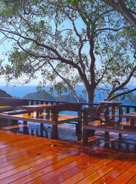 This image shows the peaceful and scenic surroundings of Deisha View, with guests sitting on a terrace overlooking Koh Tao's lush landscapes. The sunset sky adds a magical ambiance to this serene location.