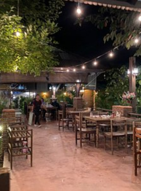 This image shows the traditional setting of Sureerat Restaurant, featuring Thai-style decor and small wooden tables. The table is adorned with vibrant green curry and other Thai delicacies served in traditional bowls. The restaurant’s cozy atmosphere and authentic dishes reflect the essence of Thai cuisine. Its welcoming vibe and flavorful food make it a popular choice for both locals and visitors.