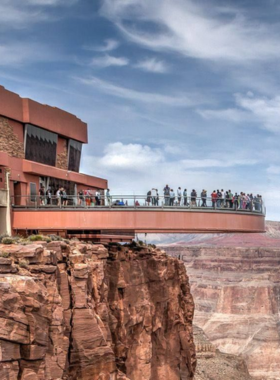 This image shows visitors walking on the Grand Canyon Skywalk, a glass bridge that extends over the edge of the canyon. Located at Grand Canyon West, the Skywalk offers an exhilarating experience where visitors can stand on the transparent glass and look down hundreds of feet to the canyon floor below. The Skywalk provides an unforgettable view of the canyon and is an exciting attraction for those seeking adventure and a unique perspective of this natural wonder."