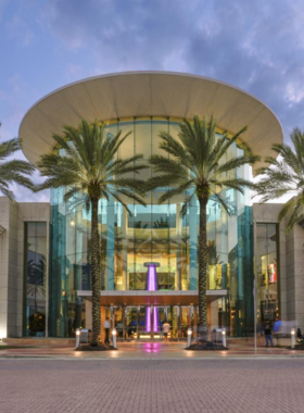 This image shows The Mall at Millenia, an upscale shopping center in Orlando, offering visitors a luxurious shopping experience with luxury brands, popular retailers, and a variety of dining options. The mall’s stylish ambiance creates an inviting environment for shopping, browsing, or simply enjoying a day out. Whether you’re looking to indulge in high-end shopping or enjoy a relaxing meal, it’s a perfect destination for those seeking a sophisticated retail experience.