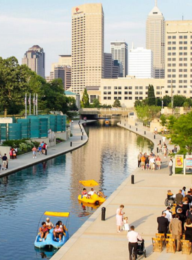 This image shows the picturesque Central Canal Walk in Indianapolis, a popular outdoor destination where visitors can enjoy peaceful walks along the canal while surrounded by nature. The image captures the serene water, lined with trees and walking paths, offering beautiful views of downtown Indianapolis. Visitors can also rent kayaks or enjoy a relaxing gondola ride along the canal. It’s a perfect place for a leisurely stroll or a peaceful break in the heart of the city, with various attractions and cafes nearby.