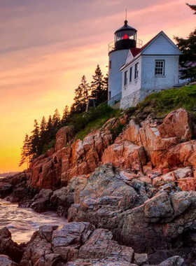 This image shows the Bass Harbor Head Lighthouse at sunset, perched on a rocky cliff overlooking the ocean. The sky is painted with vibrant shades of orange, pink, and purple as the sun sets behind the lighthouse. This iconic spot offers one of the most beautiful sunset views in Maine, and the image captures the peaceful, picturesque moment, making it a perfect way to end a day of exploration in Bar Harbor.