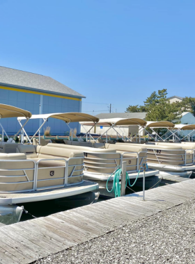 This image shows people renting kayaks and paddleboards from one of the many boat rental stations along the Ocean City boardwalk. The vibrant boats are seen floating on the calm water with people enjoying water sports and leisure activities. In the background, the Ocean City skyline and beach create a stunning contrast against the deep blue of the Atlantic Ocean. Renting a boat offers visitors an exciting way to explore the coastline and enjoy some outdoor adventure during their vacation.