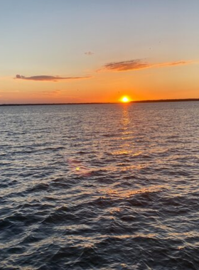 This image shows passengers on a sunset cruise in Ocean City, enjoying a peaceful boat ride as the sun sets over the horizon. The sky is filled with vibrant hues of orange, pink, and purple as the boat glides along the water, offering passengers a serene and breathtaking view of the coastline. Sunset cruises are a perfect way to unwind, relax, and take in the beauty of the ocean while experiencing the tranquility of the evening.