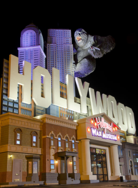 2. Visit the Hollywood Wax Museum 🎬 This image shows the Hollywood Wax Museum in Branson, Missouri, featuring lifelike wax figures of famous celebrities. A group of visitors poses for a photo with a realistic figure of Marilyn Monroe, while others interact with wax statues of movie stars like Johnny Depp and Elvis Presley. The museum's vibrant red and gold interior, with vintage film reels and Hollywood-style decor, adds to the cinematic experience. In the background, a visitor puts on a costume from the interactive props section, making the experience more fun and engaging. Bright spotlights highlight each figure, creating an authentic and star-studded atmosphere.