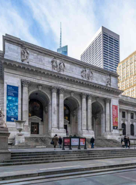 This image shows the grand entrance of the New York Public Library, an architectural masterpiece with large columns and intricate stone carvings. Inside, the Rose Main Reading Room features long wooden tables, elegant chandeliers, and towering bookshelves filled with thousands of books. Visitors sit quietly, reading or studying in the peaceful atmosphere, making it a haven for literature lovers.