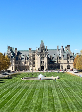 This image shows the grand Biltmore Estate, America’s largest privately owned home, surrounded by lush gardens and scenic mountain views. The château-style mansion, built in the late 1800s, features intricate architecture, stone walls, and large arched windows. The well-maintained green landscape and colorful flower beds enhance the historic charm, making it a top attraction in Asheville, North Carolina.

