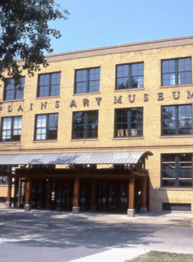 This image shows the Plains Art Museum, a famous art gallery in Fargo, North Dakota. The museum's modern interior is filled with contemporary paintings, Native American artwork, and large sculptures. Visitors can be seen admiring exhibitions, discussing artworks, and participating in hands-on creative workshops. The museum has a peaceful, educational atmosphere with bright lighting and beautifully displayed art collections that showcase the region’s rich artistic heritage and cultural history.