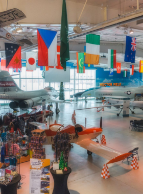 This image shows the Fargo Air Museum, where visitors can explore historic and modern aircraft. The large, well-lit hangar is filled with World War II planes, jet fighters, and aviation exhibits. Guests are seen walking around, reading informational plaques, and sitting inside aircraft cockpits. The museum offers a hands-on learning experience, with aviation enthusiasts and families engaging with pilots and aviation experts to understand the history and technology of flying machines.