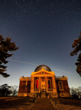 This image shows the historic Cincinnati Observatory, known as the "Birthplace of American Astronomy," featuring one of the oldest working telescopes in the country. The building has a classic domed structure, allowing stargazers to observe celestial wonders like Saturn’s rings and the moon’s craters. During special events, visitors gather for telescope viewings, astronomy talks, and educational programs under the night sky. The observatory’s peaceful setting, with clear views of the stars, offers a unique experience for space enthusiasts, families, and anyone curious about the universe.