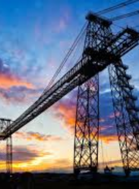 This image shows the Newport Transporter Bridge, a historic engineering marvel built in 1906. The bridge features tall steel towers and a suspended platform that carries people and vehicles across the River Usk. The structure’s unique design makes it one of the last of its kind in the world. Visitors can climb to the top for a panoramic view of Newport, enjoying the breathtaking sights from this iconic landmark.