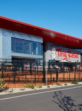 This image shows the vibrant atmosphere of Tiny Rebel Brewery, an award-winning craft beer brewery in Newport. The taproom has an industrial-style design, with wooden tables, colorful murals, and a variety of beer taps. Visitors can enjoy freshly brewed pints, including IPAs, stouts, and unique experimental flavors. The brewery is a popular hangout spot where people can relax, socialize, and taste some of the best beers in Wales.