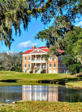 This image shows Drayton Hall, an 18th-century plantation house in Charleston, preserved in its original condition. The image features the grand house surrounded by expansive grounds and gardens, offering visitors a glimpse into the past. The plantation’s history is significant, as it remained largely untouched through the years. Visitors can explore the house’s period rooms and learn about the history of the property, which has played an important role in Charleston’s history during the Revolutionary and Civil War periods.