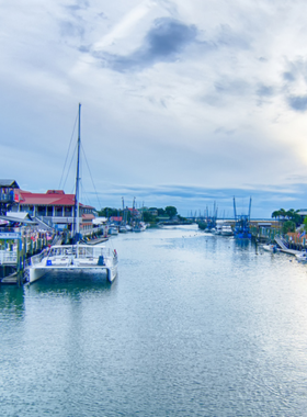 This image shows a sunset sail on Charleston Harbor, with the orange and pink hues of the setting sun reflecting off the calm waters. The sailboat glides peacefully through the harbor, with the historic skyline and Fort Sumter visible in the distance. The image captures the serene beauty of Charleston’s waterfront, providing visitors with an unforgettable experience of the harbor at twilight. The tour allows guests to take in the sights while enjoying the cool breeze and stunning scenery.