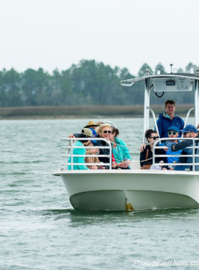 This image shows an eco-friendly boat tour in Charleston Harbor, where visitors are exploring the waterways in search of dolphins, seabirds, and other marine life. The boat glides through the calm waters, offering a close-up view of the natural beauty of Charleston’s coastal ecosystem. In the background, Morris Island Lighthouse can be seen, while the surrounding waters teem with wildlife. The eco boat tour is both an educational and scenic experience, providing an opportunity to appreciate Charleston’s diverse environment.