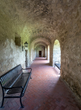 This image shows the historic Alamo, an iconic mission-style building with weathered stone walls and arched doorways. Visitors are seen exploring the site, walking through the historic grounds where the famous 1836 battle took place. The Texas flag waves in the background, symbolizing the fight for independence. The peaceful yet powerful setting reminds visitors of the bravery and resilience that shaped Texas history.