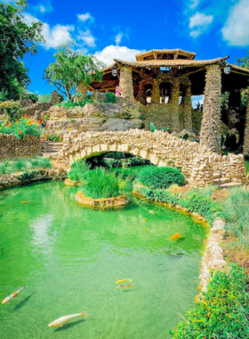 This image shows the serene beauty of the Japanese Tea Garden in San Antonio, featuring a cascading waterfall, koi-filled ponds, and lush greenery. A stone bridge crosses over the pond, leading to a pagoda-style pavilion where visitors relax and enjoy the peaceful atmosphere. The garden’s carefully manicured landscapes provide a perfect escape from the city's hustle and bustle, ideal for meditation and quiet reflection.