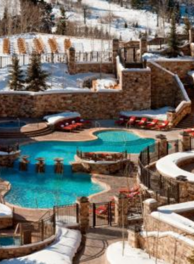 This image captures the luxurious spa experience at The St. Regis Deer Valley, where guests indulge in relaxation amidst a breathtaking mountain setting. A woman reclines in a plush robe, sipping herbal tea by a large window that overlooks snow-covered peaks. The spa’s heated infinity pool shimmers under the soft glow of sunset, inviting visitors for a soothing soak. Inside, a massage therapist prepares a cozy treatment room with candles and essential oils. The spa menu includes facials, body treatments, and deep tissue massages, perfect for unwinding after outdoor adventures. The image perfectly highlights the elegance and serenity of The St. Regis Deer Valley Spa, offering the ultimate escape in Park City.