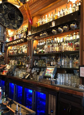 This image showcases the lively and energetic atmosphere of No Name Saloon, one of Park City’s most iconic nightlife spots. The bar’s rustic interior is filled with patrons enjoying drinks, conversation, and laughter. A bartender is seen pouring a craft beer from the tap while a group of friends raises their glasses in a celebratory toast. The warm glow of hanging Edison lights adds a cozy ambiance, while vintage décor and buffalo-themed memorabilia reflect the bar’s unique character. Outside, the rooftop patio is packed with visitors enjoying cocktails and breathtaking views of Main Street’s historic buildings. A live musician plays in the background, adding to the vibrant scene. The image captures the excitement and charm of No Name Saloon, making it the perfect place for both locals and tourists to unwind, socialize, and end their Park City adventure on a high note.