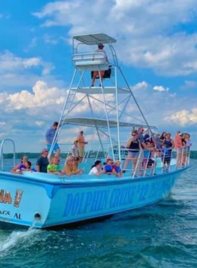 This image shows an exciting dolphin cruise off the coast of Gulf Shores. The boat cuts through calm waters as playful dolphins leap and swim alongside it, delighting passengers. The image captures the joy of watching dolphins in their natural habitat, with the open sky and sparkling water providing a perfect backdrop. The tour offers a unique wildlife experience, bringing nature lovers and families up close to these magnificent creatures.