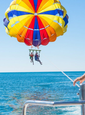 This image shows a thrilling parasailing adventure in Gulf Shores, with a person soaring above the sparkling waters. The parasail catches the wind as the rider enjoys panoramic views of the coastline. In the distance, you can spot dolphins swimming, adding to the excitement. The image conveys the rush of parasailing and the breathtaking perspective it offers over Gulf Shores’ natural beauty.